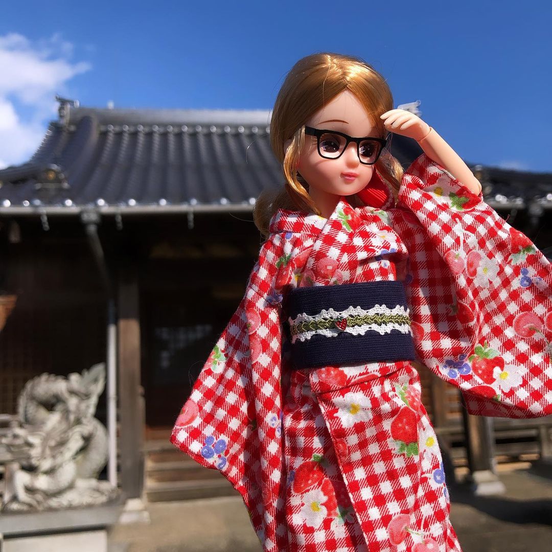 blonde Licca doll with her hair up in an elaborate ponytail wearing a red gingham yukata